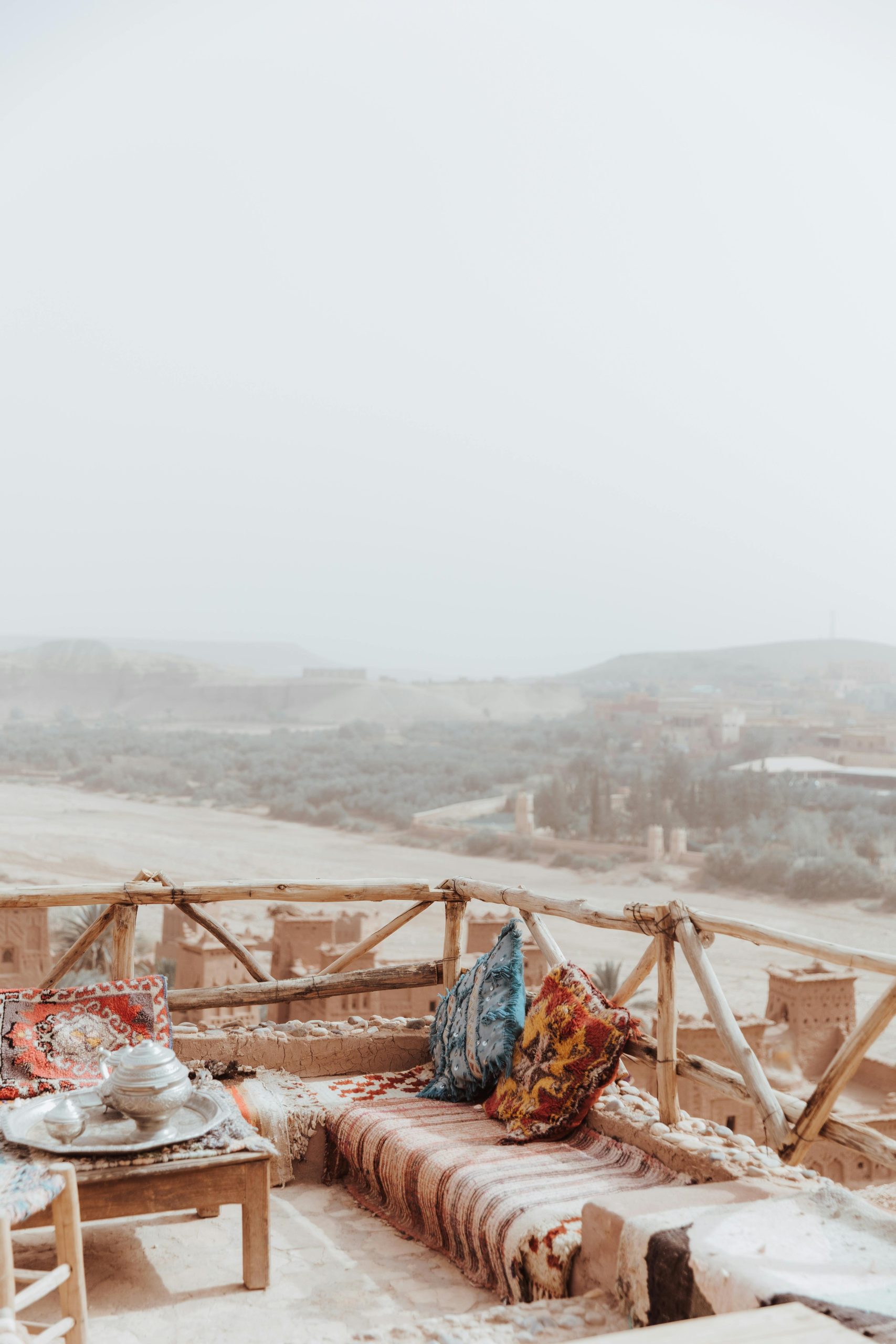 A peaceful terrace with colorful cushions overlooking Ait Ben Haddou's desert landscape in Morocco.